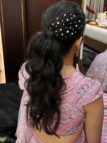 A close-up of a wavy high ponytail adorned with scattered pearls. This is a chic and trendy hairstyle for a sangeet or cocktail party, adding a touch of playful elegance.