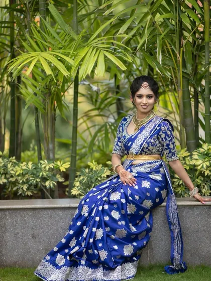 A full-length view of the bride in her royal blue ensemble, seated gracefully. The outfit is a perfect choice for a grand wedding reception.