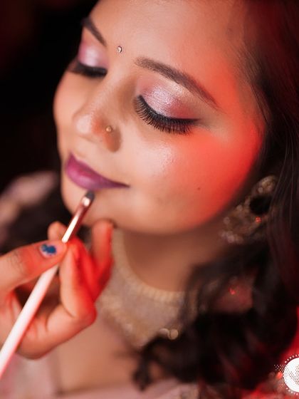 A close-up of the makeup application process for Kajol's reception. This shot focuses on the precise application of lipstick, a crucial final step.