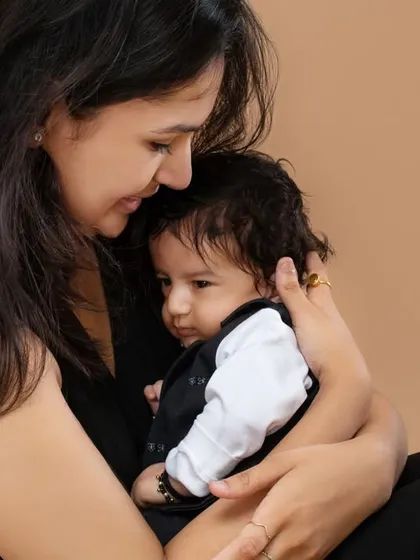 The special bond between a mother and her child. This tender moment shows a mother holding her baby close, a simple and powerful portrait against a clean, neutral background.