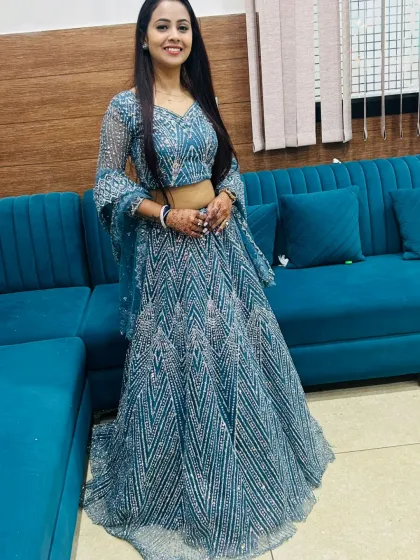 A client looking elegant in a teal lehenga with geometric silver sequin work. The bell sleeves on the choli add a modern touch.