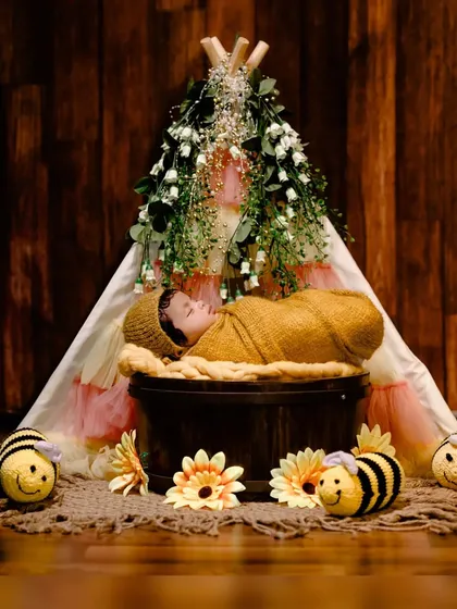 A sweet 'bumblebee' themed newborn shoot, with the baby sleeping soundly in a basket inside a floral teepee, surrounded by crocheted bees.