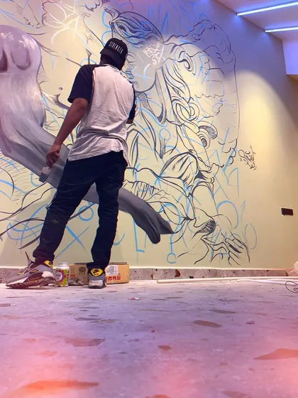 Me in action, working on a large monochrome mural of a romantic, angelic couple. This angle shows the scale of the piece and the initial line work before shading.