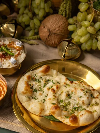 Soft, fluffy naan bread with a hint of garlic and herbs, served on a brass plate as part of our celebratory Diwali feast.
