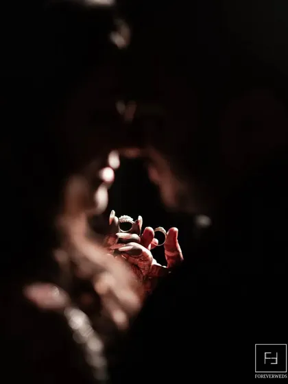 A creative and artistic shot focusing on the wedding rings. This is about finding unique perspectives to tell your story, symbolizing the union and the promises exchanged.