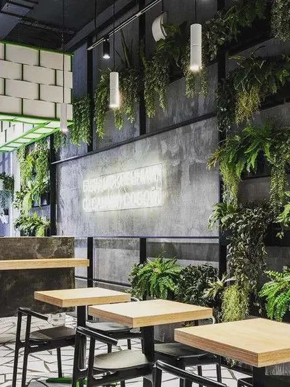 The right plants can completely define the mood of a space. For this modern restaurant, we used a variety of hanging ferns and wall-mounted greenery to complement the industrial-chic interiors, creating an inviting and memorable dining experience.