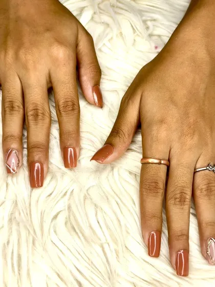 A warm brown gel polish on square-shaped extensions, featuring a geometric accent nail with negative space for a modern touch.
