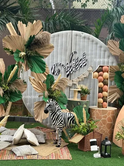 A "Wild One" first birthday with a boho-jungle aesthetic. This setup uses natural textures like dried palm leaves, pampas grass, and wood, along with animal props, to create a stylish and adventurous atmosphere.