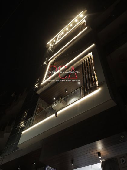 A dramatic low-angle view of 'The Cursive Abode' at night. This perspective highlights the cantilevered balcony and the continuous flow of the architectural lighting.