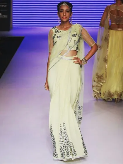 A moment from the runway featuring a lime yellow georgette saree. The design is elevated with delicate butterfly motifs and Swarovski crystal detailing, blending modern style with classic elegance for a high-fashion statement.