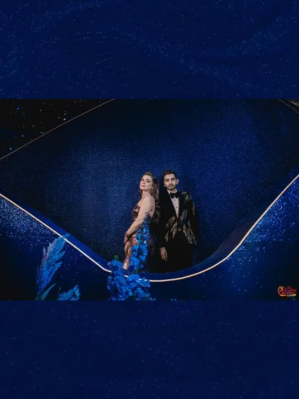 The couple posing against a custom-designed, glittering blue backdrop with subtle light accents, creating a sophisticated and thematic portrait moment.