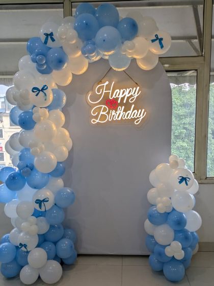 The little bow details on the balloons add a charming and cute element to this blue and white setup.