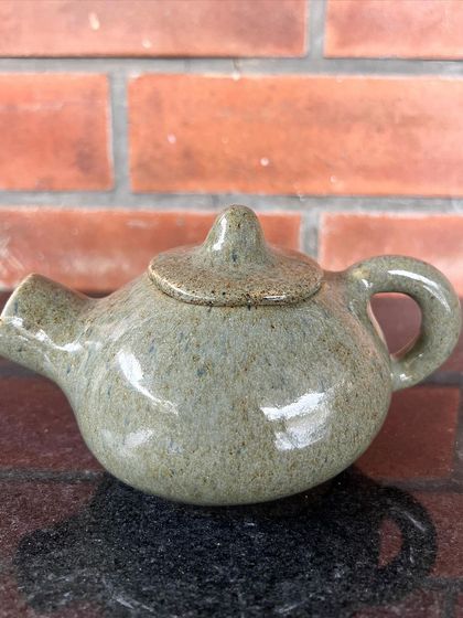 A miniature teapot with a simple, speckled glaze. Even small pieces require a great deal of skill to create on the wheel.