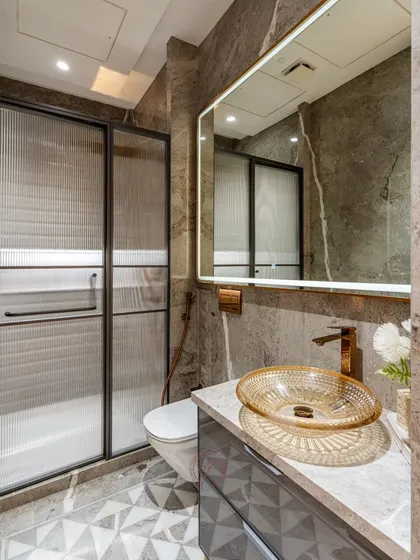 A full view of the vanity area, showcasing the unique textured glass basin and the elegant combination of grey marble and gold accents.
