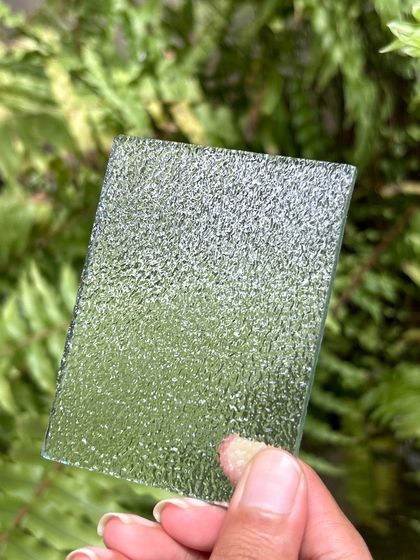 A close-up of a textured glass sample. We use different types of glass to play with light and privacy, from clear to frosted to patterned, depending on the functional and aesthetic needs of the space.