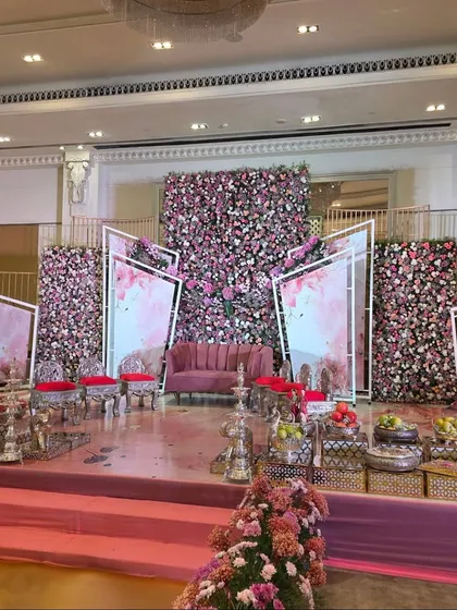 A modern stage design with pink floral walls and abstract white frames for a contemporary engagement party.
