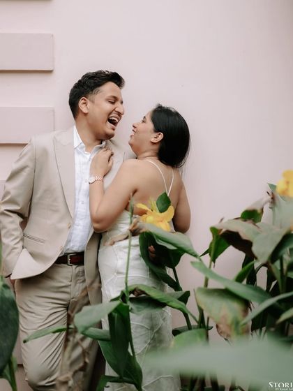 Another joyful, laughing portrait of the couple against a pink wall, capturing their playful chemistry.