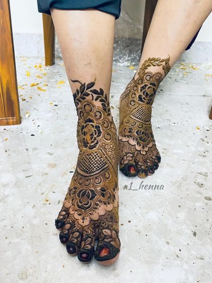 A modern take on bridal foot henna, with a bold floral motif on the ankle and intricate patterns covering the foot.