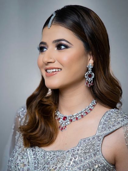 A smiling portrait of the model in the silver-grey lehenga, showing how the ruby necklace adds a pop of color.