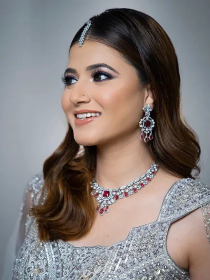 A smiling model wearing the ruby and zircon set. The pop of red adds a touch of romance and drama to the cool-toned outfit.