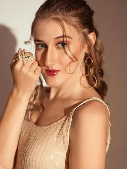 A close-up shot focusing on the jewelry and makeup. The hard light creates a beautiful highlight on the skin.