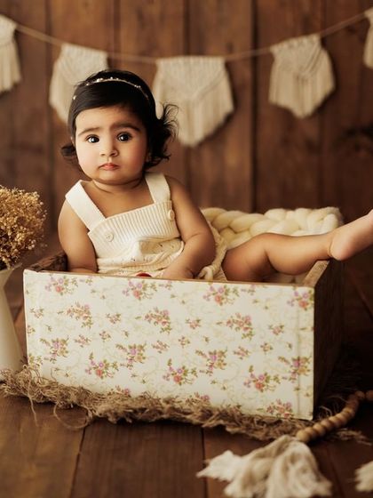 This toddler is exploring the studio, and I'm there to capture it. The floral box and rustic background create a beautiful scene.