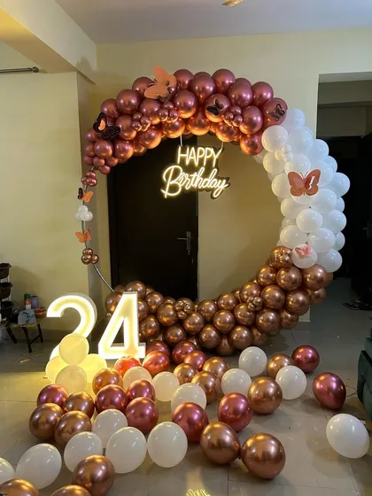 This is a duplicate of ID 10, 76, 81, 120, 210. An elegant and modern ring backdrop is perfect for home celebrations. The setup features a circular frame with a rose gold and white chrome balloon arrangement, a 'Happy Birthday' neon sign, and a light-up marquee number '24'.