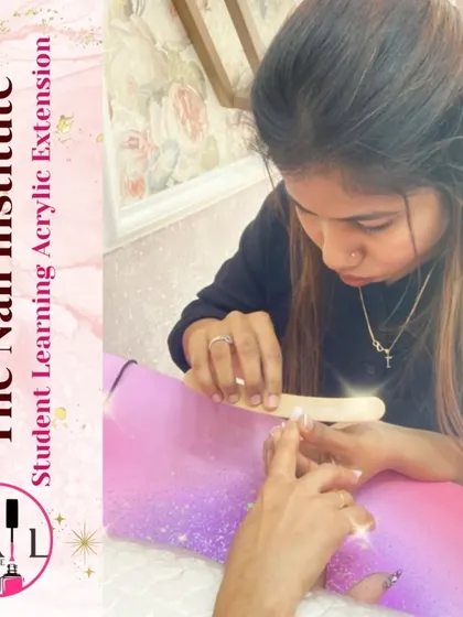 A student carefully files and shapes an acrylic extension, ensuring the final result is smooth and perfectly contoured.