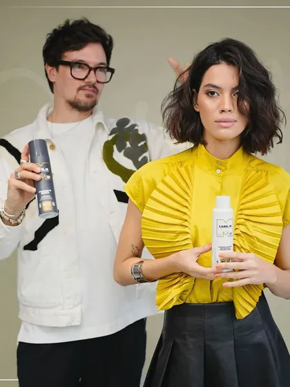 Jon Wilsdon and his model pose with the Label.M products used to create this forward graduation look. This image connects the technique to the tools, showing students the synergy between skill and professional products.