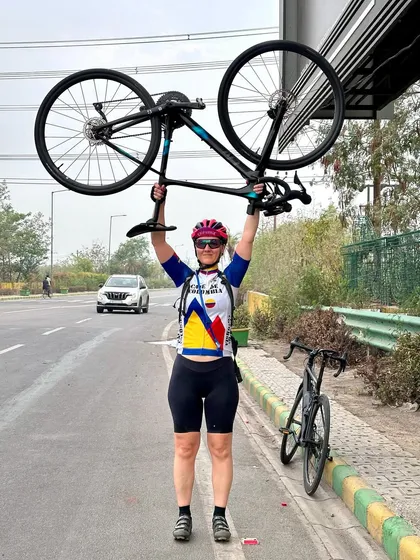 A triumphant pose, lifting her bike overhead after a challenging ride.