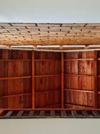 A view from the stairwell of the Vinaya residence, showing the layers of natural materials. The rich tones of the polished wooden wall panels contrast beautifully with the textured clay tile ceiling.