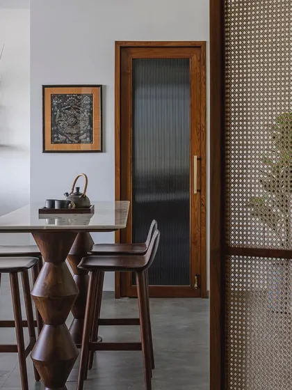 A sneak peek into the 'Sepalika' office, where a high table with sculptural wooden legs serves as a casual meeting or break area. The design combines the timeless charm of cane and wood with modern functionality.