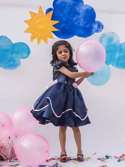 A playful moment in a classic navy party dress. The full skirt has a beautiful swing, and the pink floral accents add a pop of color and sweetness.