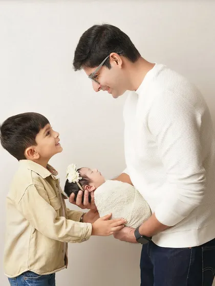 A beautiful moment as a father and older son together hold the newest member of the family. This photo captures the growing family bond.