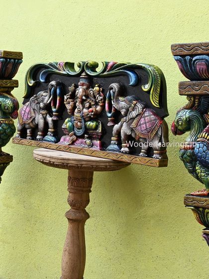Another angle of the Gaja Ganesh panel and parrot brackets, highlighting the vibrant colors and three-dimensional quality of the carvings.