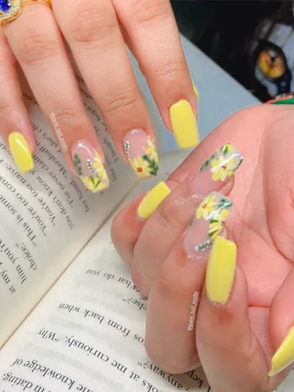 When in doubt, add flowers. This cheerful set features bright yellow nails paired with accent nails showcasing hand-painted daisies on a sheer background.