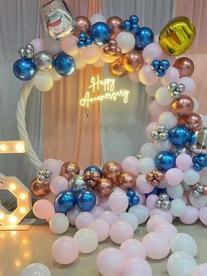 A 5th-anniversary celebration with a circular balloon arch in blue, pink, and rose gold, and a '5' marquee light.