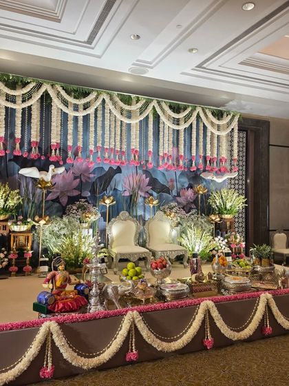 A beautiful stage with a painted backdrop of a lotus pond, complemented by hanging tuberose garlands.