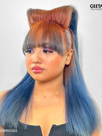A close-up of the final avant-garde hairstyle. This look combines a vibrant orange and blue color melt with a structural bow, showcasing the advanced styling techniques taught at the academy.