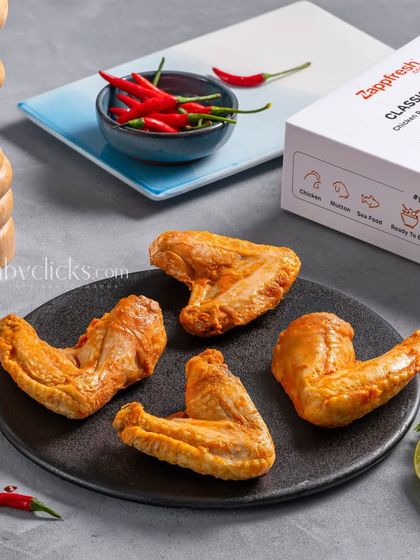 Cooked chicken wings from Zappfresh, plated with the product box and fresh red chilies.