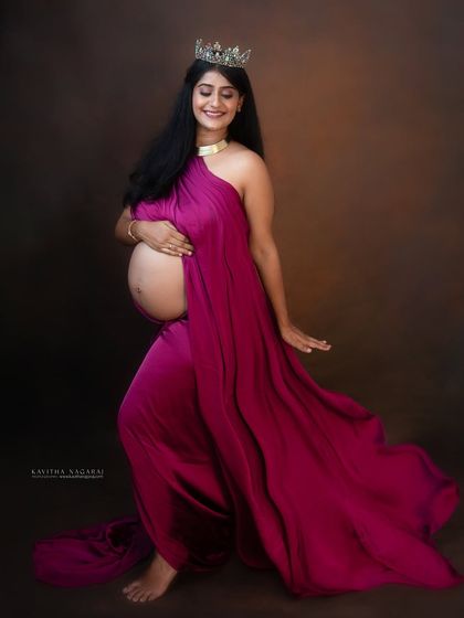 Be the princess of your own fairy tale. This expecting mother looks radiant in a flowing magenta gown and crown, a perfect way to celebrate the magic of pregnancy.
