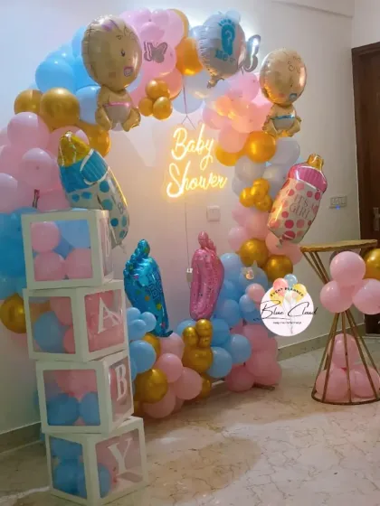 A vibrant gender reveal baby shower setup with a balloon ring, 'BABY' blocks, and a neon sign.