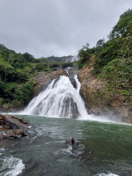 A ground-level view of Dudhsagar Falls, showing the river and the cascading water. Our treks take you right to the heart of the action.