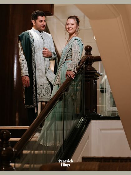 A grand portrait of the couple on a staircase. Their elegant, coordinated outfits and poised stances create a look of timeless sophistication.