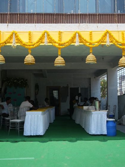 A closer look at the entrance decor for a housewarming. The bright yellow structure adorned with marigold garlands and traditional bells creates a festive and auspicious welcome.