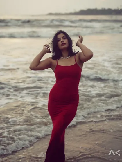 A collection of portraits featuring a model in a red dress on the rocks and by the water. The series explores different poses and moods, from serene to powerful.