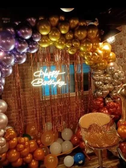 An 18th birthday setup in a cafe, designed to feel trendy and celebratory. I used a mix of metallic chrome balloons in purple, gold, and rose gold to create a rich arch, complemented by a shimmery curtain and a neon sign.