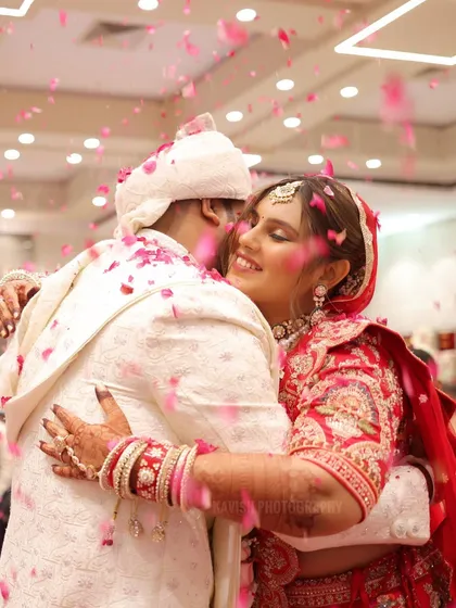 A purely candid moment of joy as the bride hugs the groom, showered in a rain of pink flower petals. These are the unscripted, emotional memories I aim to preserve.
