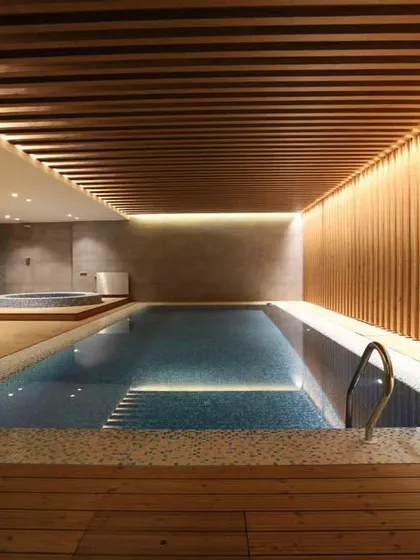 Wood cladding and decking can transform an indoor pool area into a luxurious spa-like environment. The wooden slats on the ceiling and wall add warmth and texture.