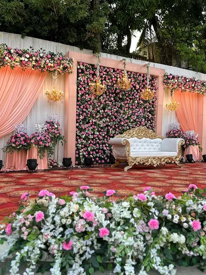 We designed this classic and romantic reception stage, featuring a dense wall of pink and white roses. The elegant drapes, vintage-style sofa, and sparkling chandeliers added a touch of royal grandeur to the evening.